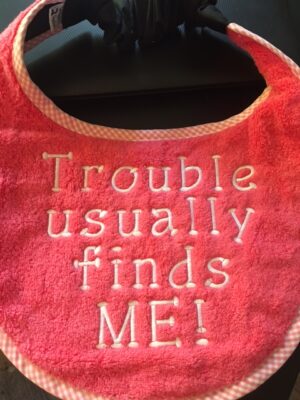 Adult bib in two colours with slogan"Trouble Usually Finds me"