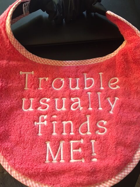 Adult bib in two colours with slogan"Trouble Usually Finds me"