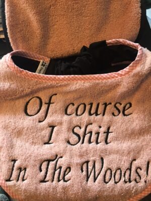 Adult Bib in baby pink with slogan "Of Course I Shit in the Woods"